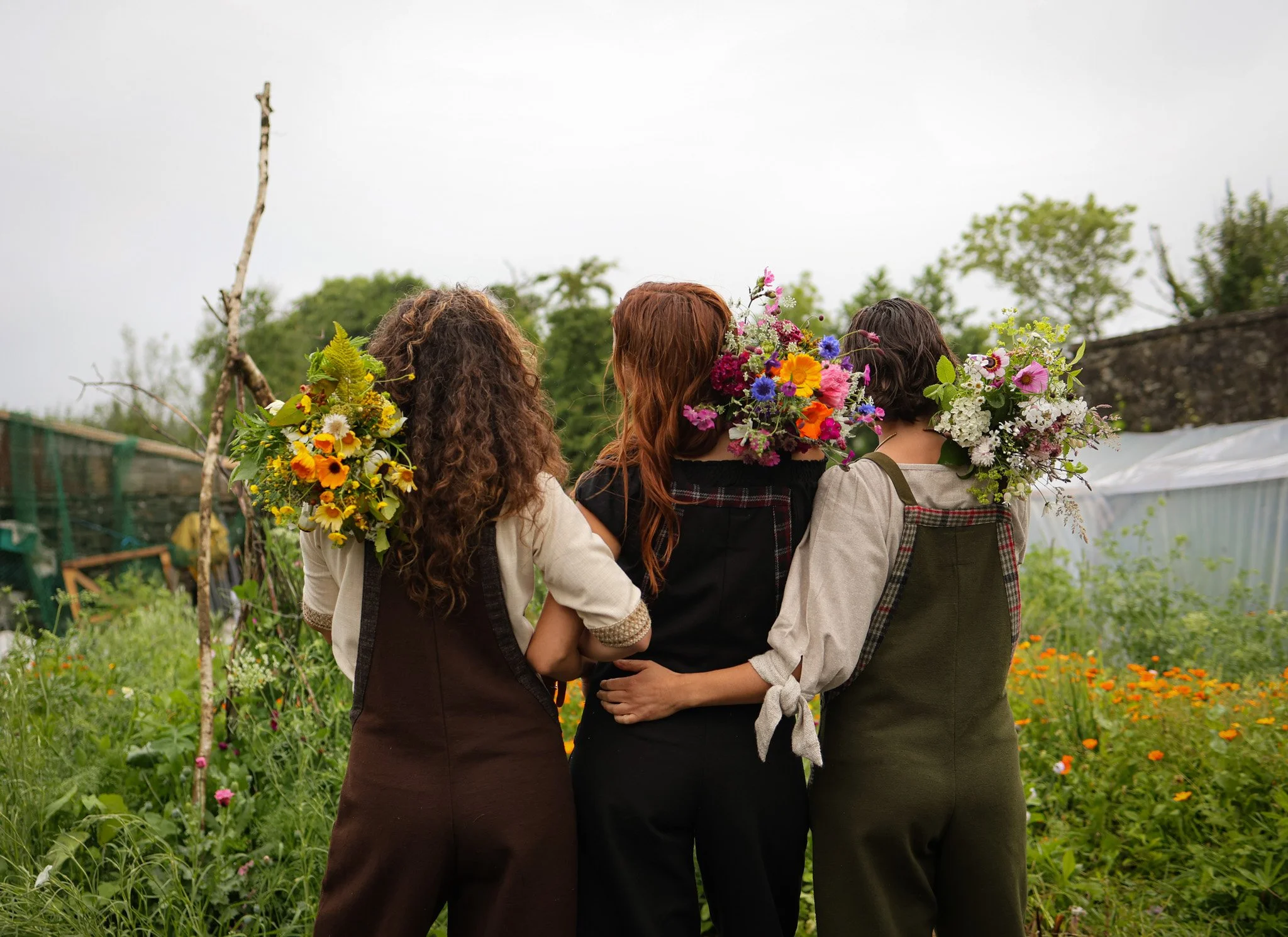 Three girls in a flower garden wearing dungarees